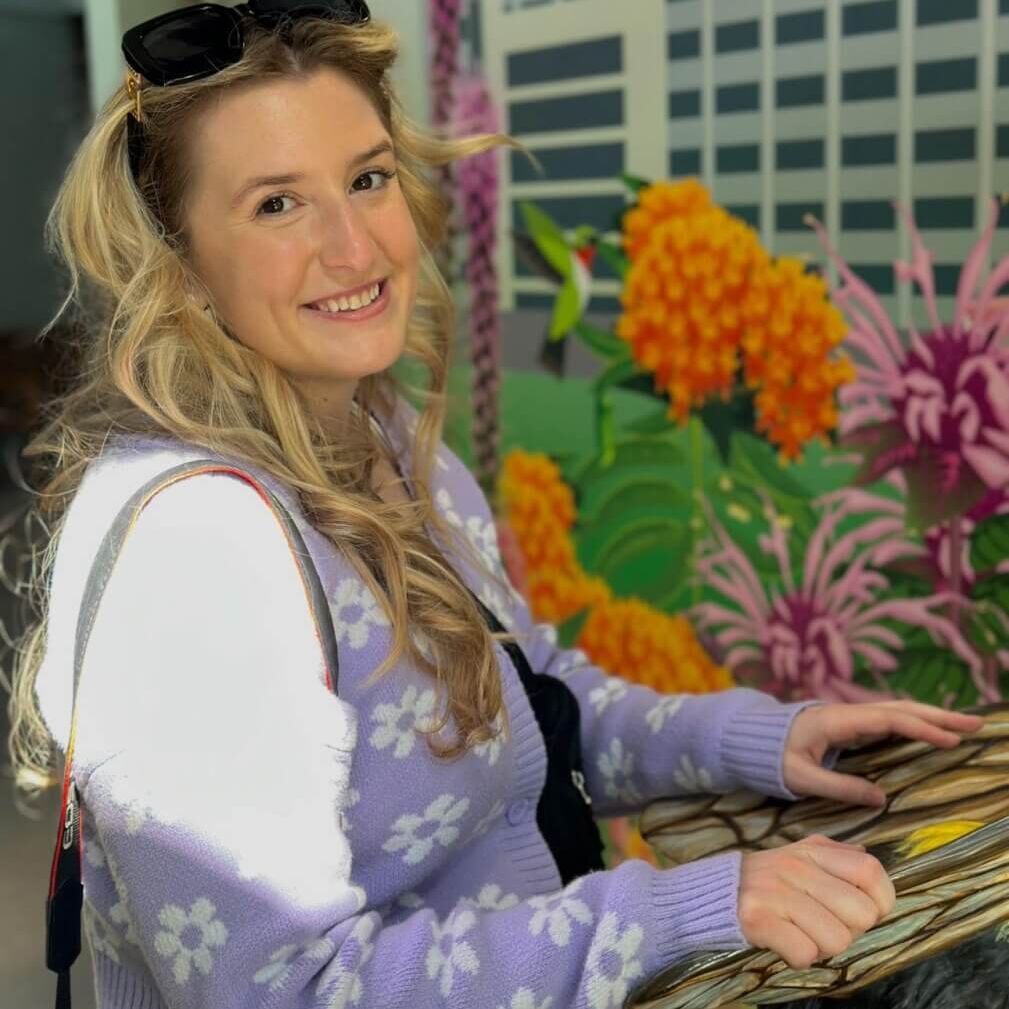 Alexa smiling, wearing a purple floral sweater and white shirt in a professional headshot.
